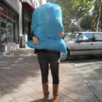 Frau trägt großen Müllsack, der ihr Gesicht verdeckt