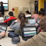 Schulklasse arbeitet mit Laptops und Smartboard