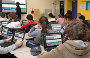Schulklasse arbeitet mit Laptops und Smartboard